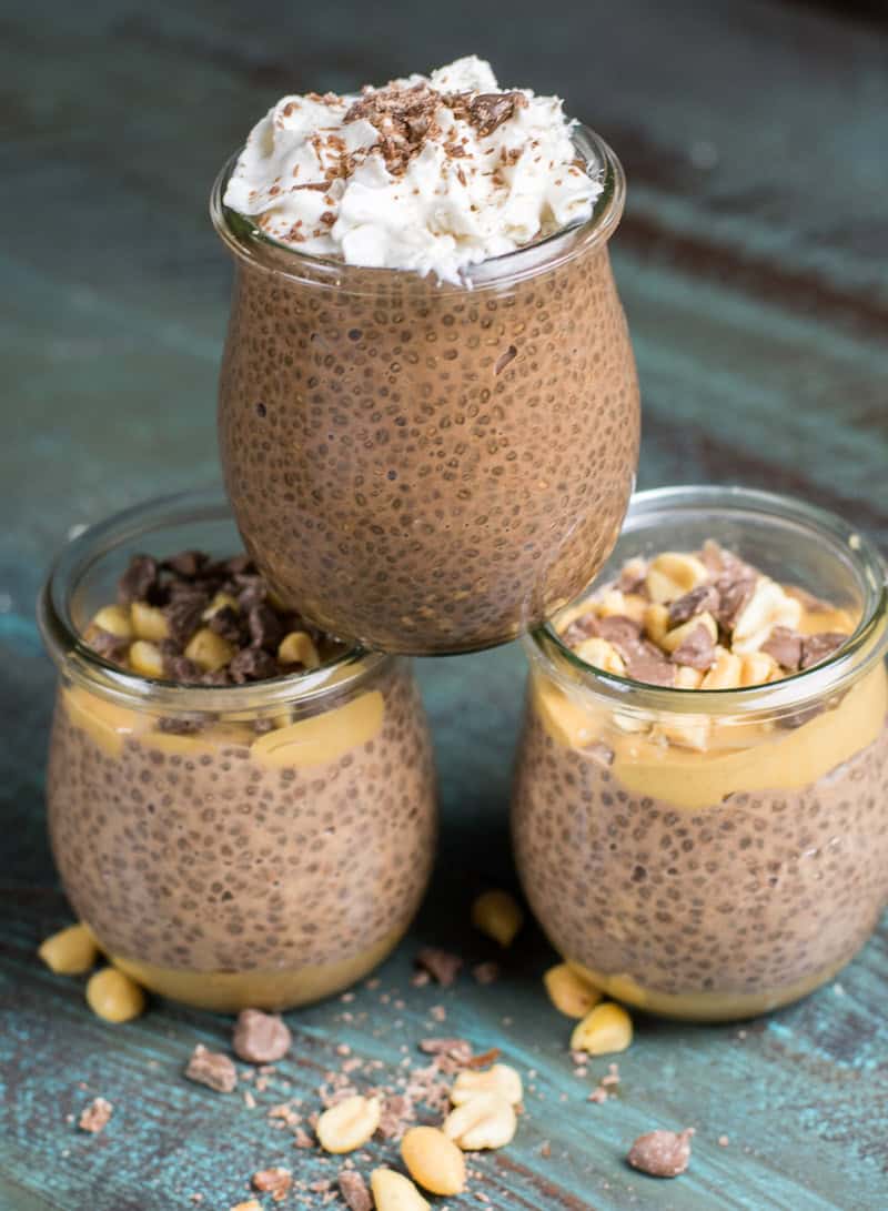 three jars of easy chia pudding on a teal wood countertop