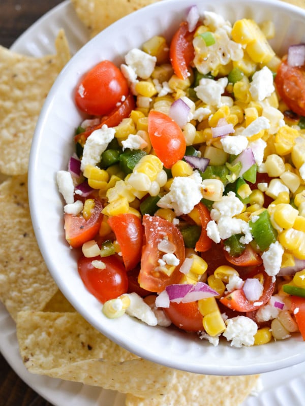 This Sweet Corn Salsa is a summer staple! Packed with grilled sweet corn, fresh tomatoes and lime juice, this is a salsa you will love on chips, tacos and wraps!
