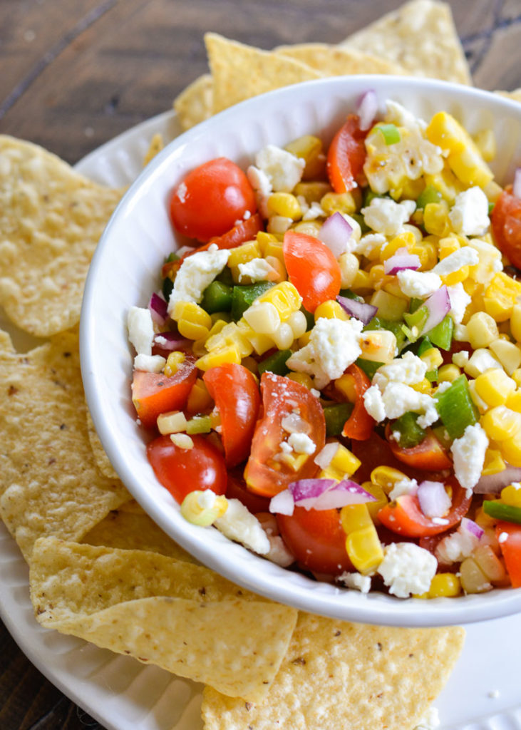 This Sweet Corn Salsa is a summer staple! Packed with grilled sweet corn, fresh tomatoes and lime juice, this is a salsa you will love on chips, tacos and wraps!