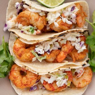 shrimp tacos with slaw on plate with limes