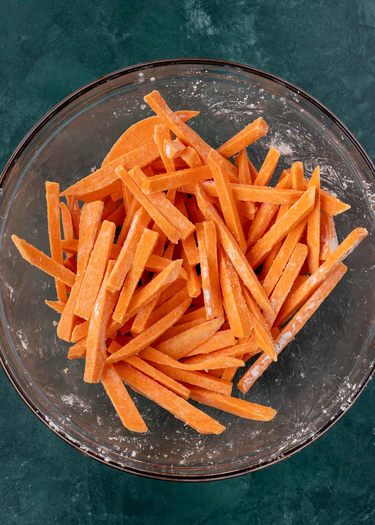 Corn starch on sweet potato fries in mixing bowl
