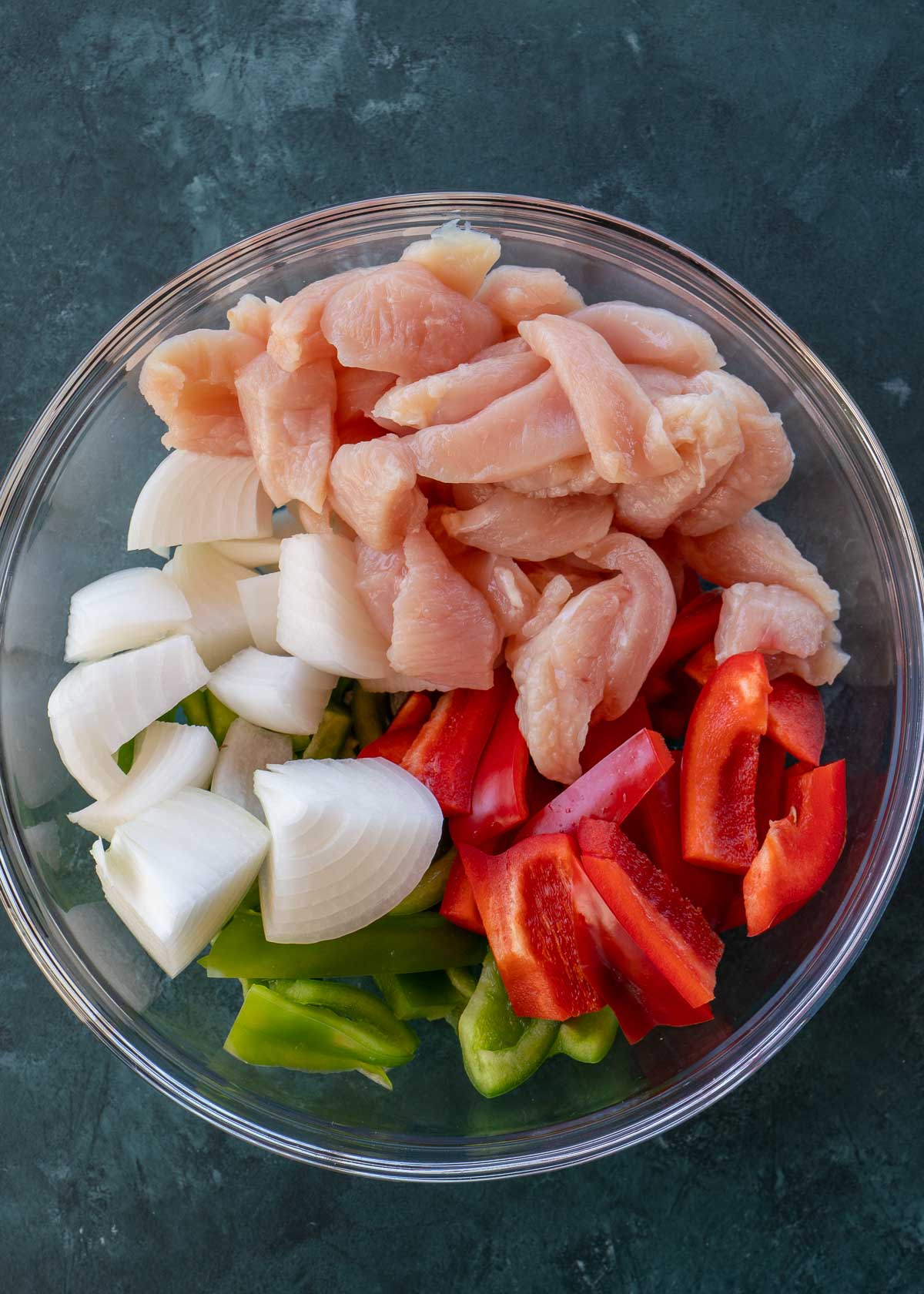 sliced chicken and vegetables in mixing bowl.