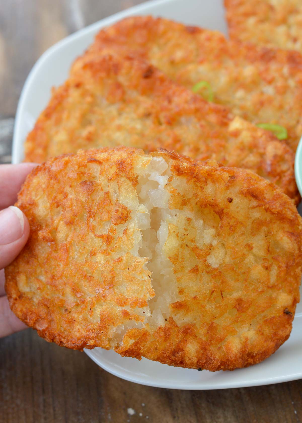 crispy hash brown torn in half on a white plate with soft, tender potato interior showing