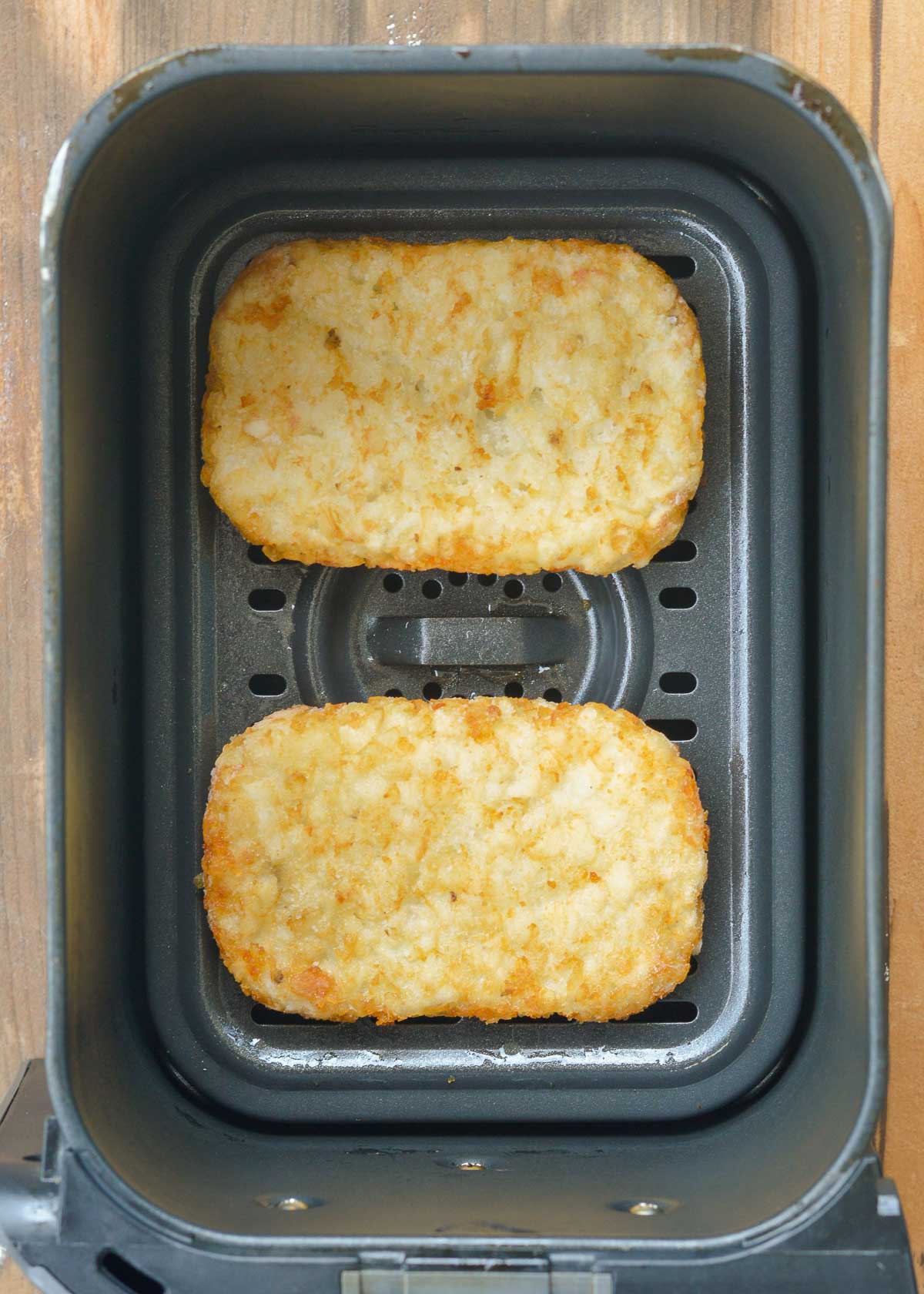 uncooked, frozen hash brown patties in an air fryer basket