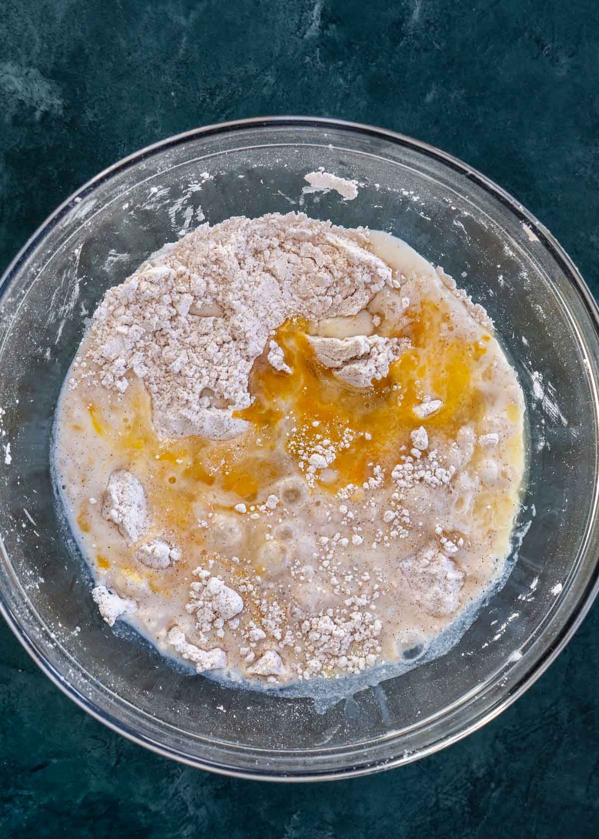 eggs, milk, and vanilla extract added to dry fritter ingredients in a glass bowl