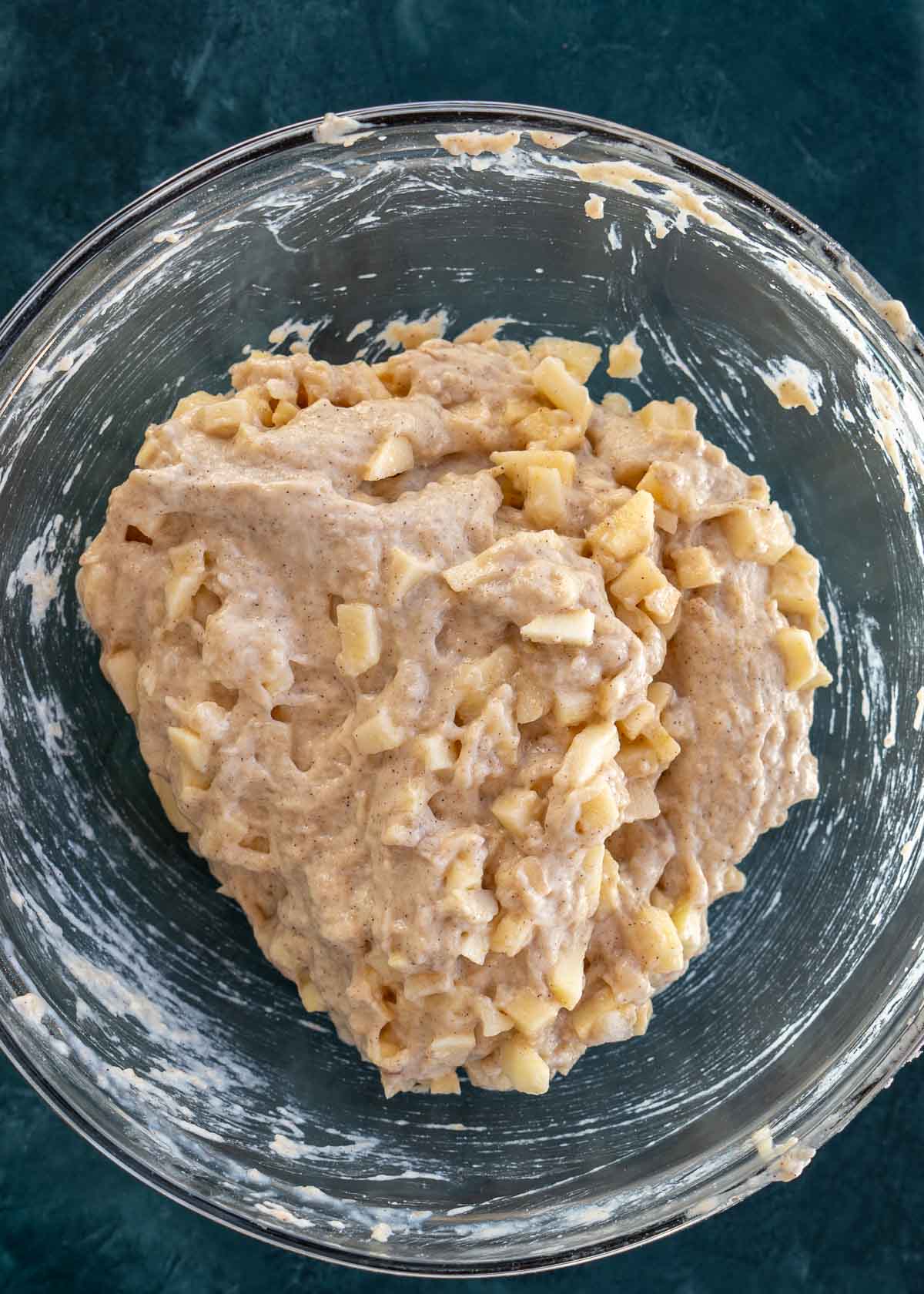 apples folded into the fritter batter in a bowl