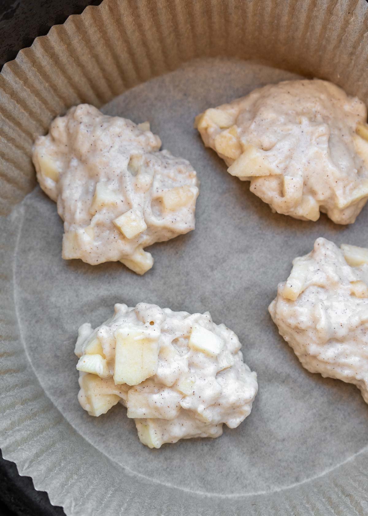 apple fritters on a liner in the air fryer bucket