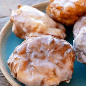 four glazed air fryer apple fritters on a teal plate