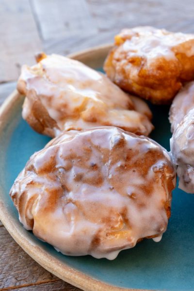 four glazed air fryer apple fritters on a teal plate