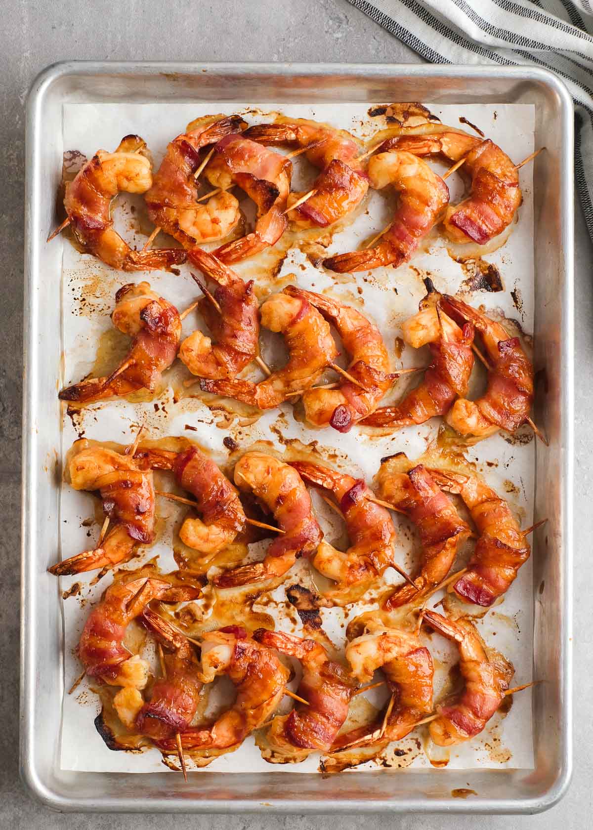 cooked bacon wrapped shrimp with bbq sauce on a baking sheet