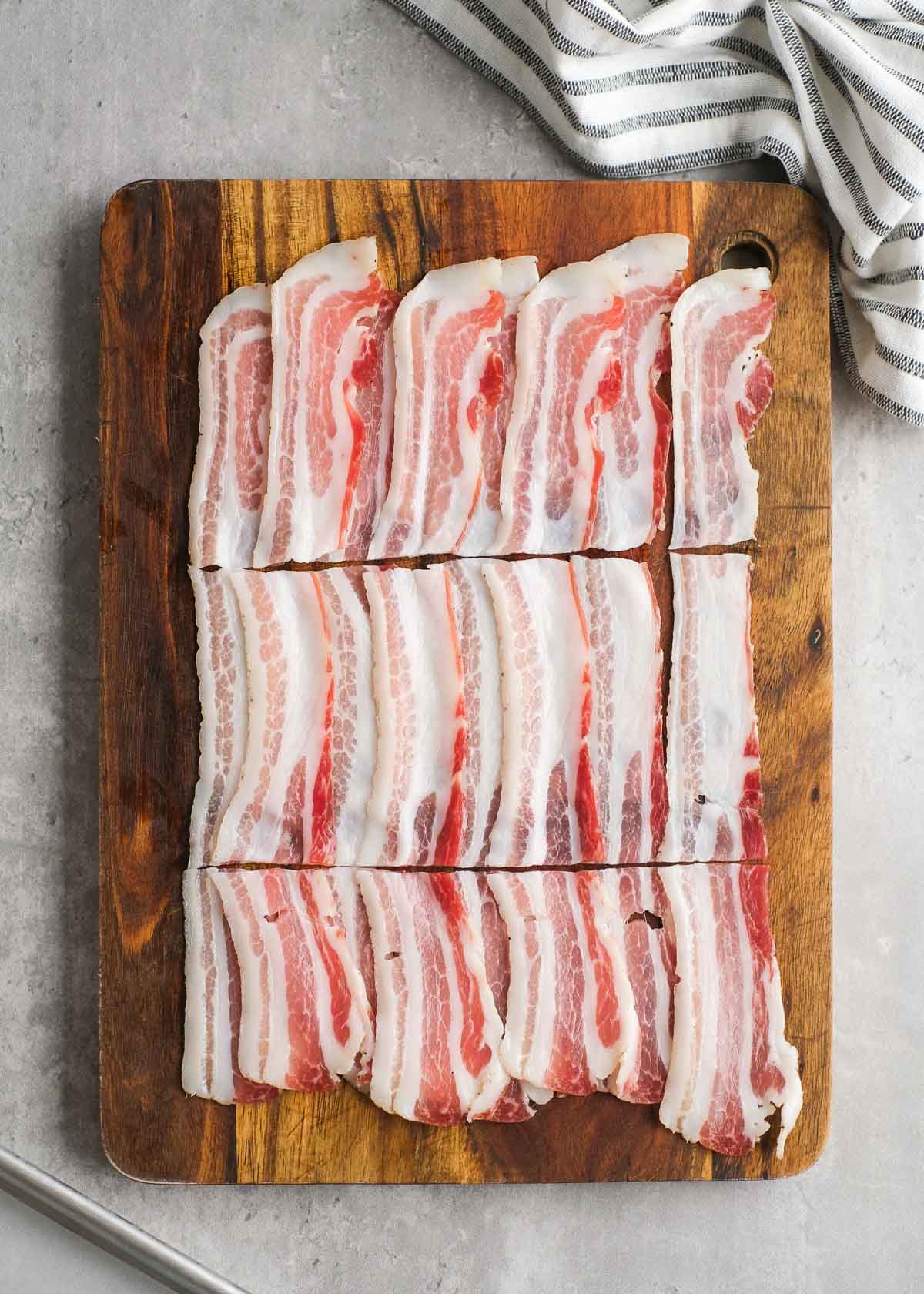 bacon cut into thirds on a cutting board