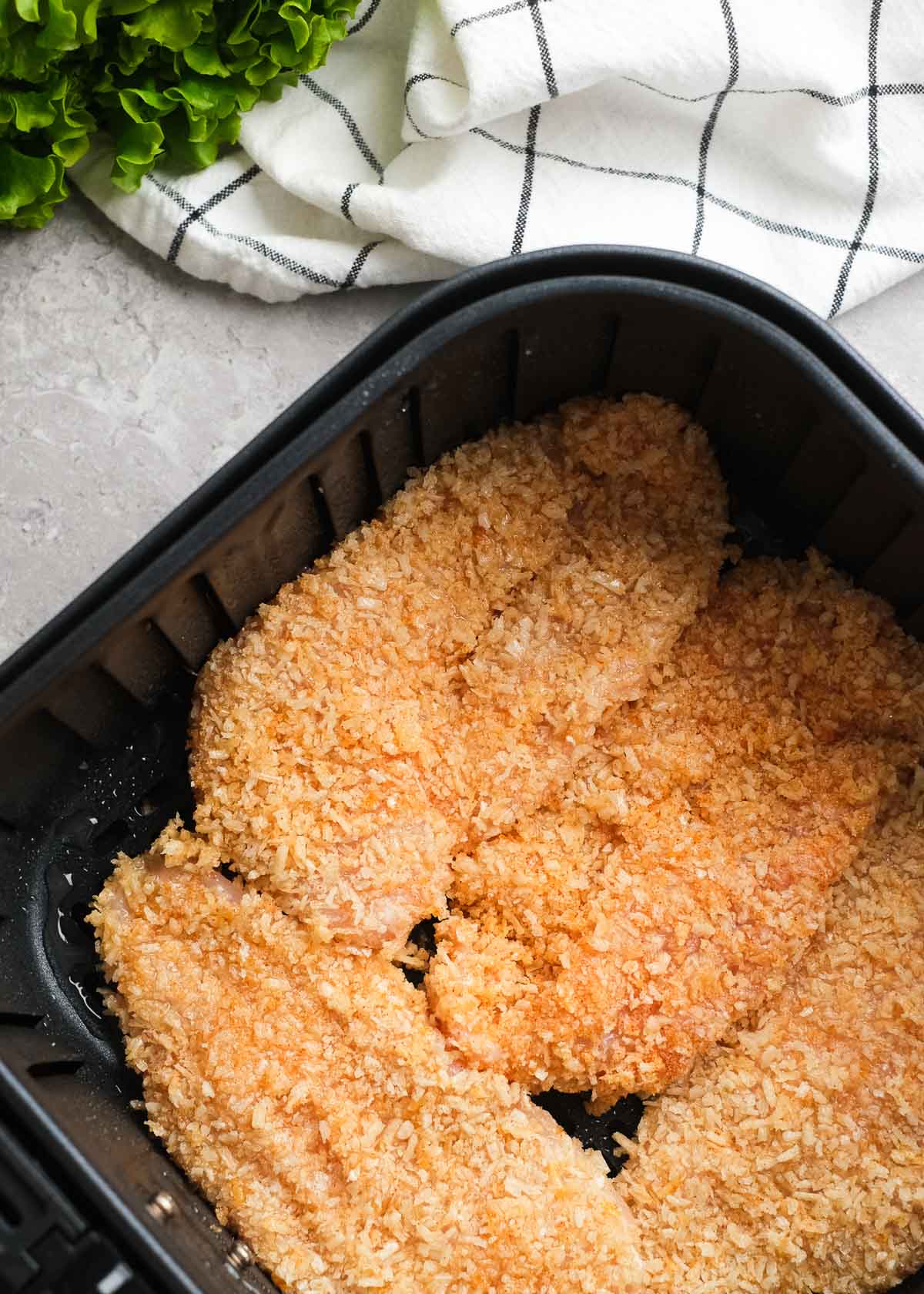breaded chicken fillets in an air fryer basket