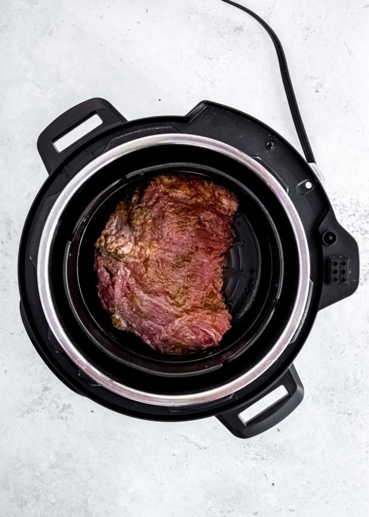 an uncooked flank steak in an air fryer