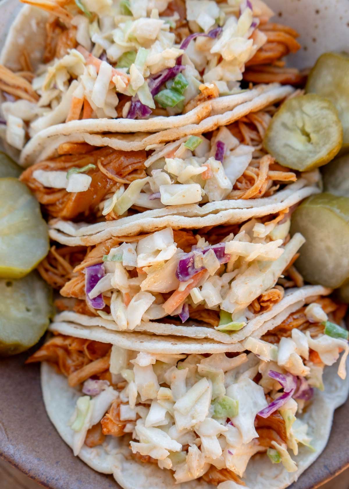 four juicy bbq chicken tacos loaded with slaw and pickles