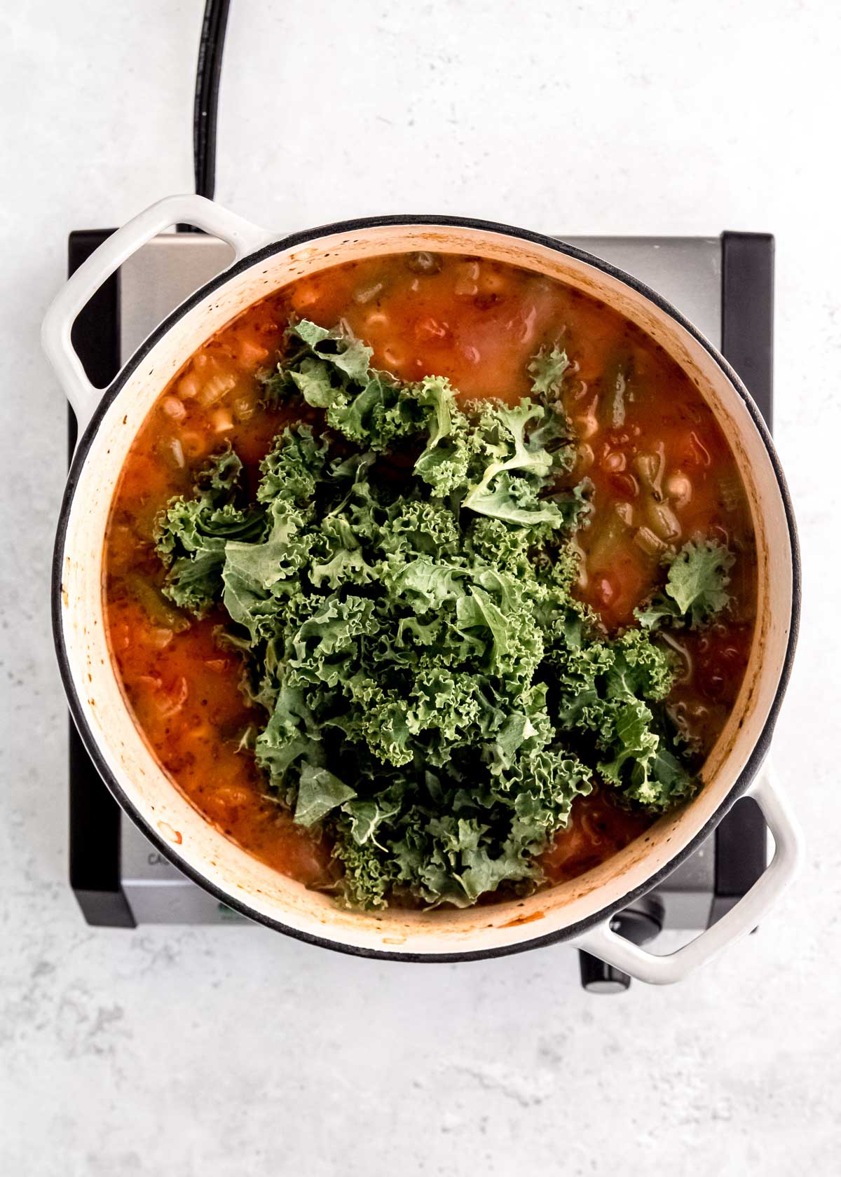 kale placed in the pot of minestrone soup