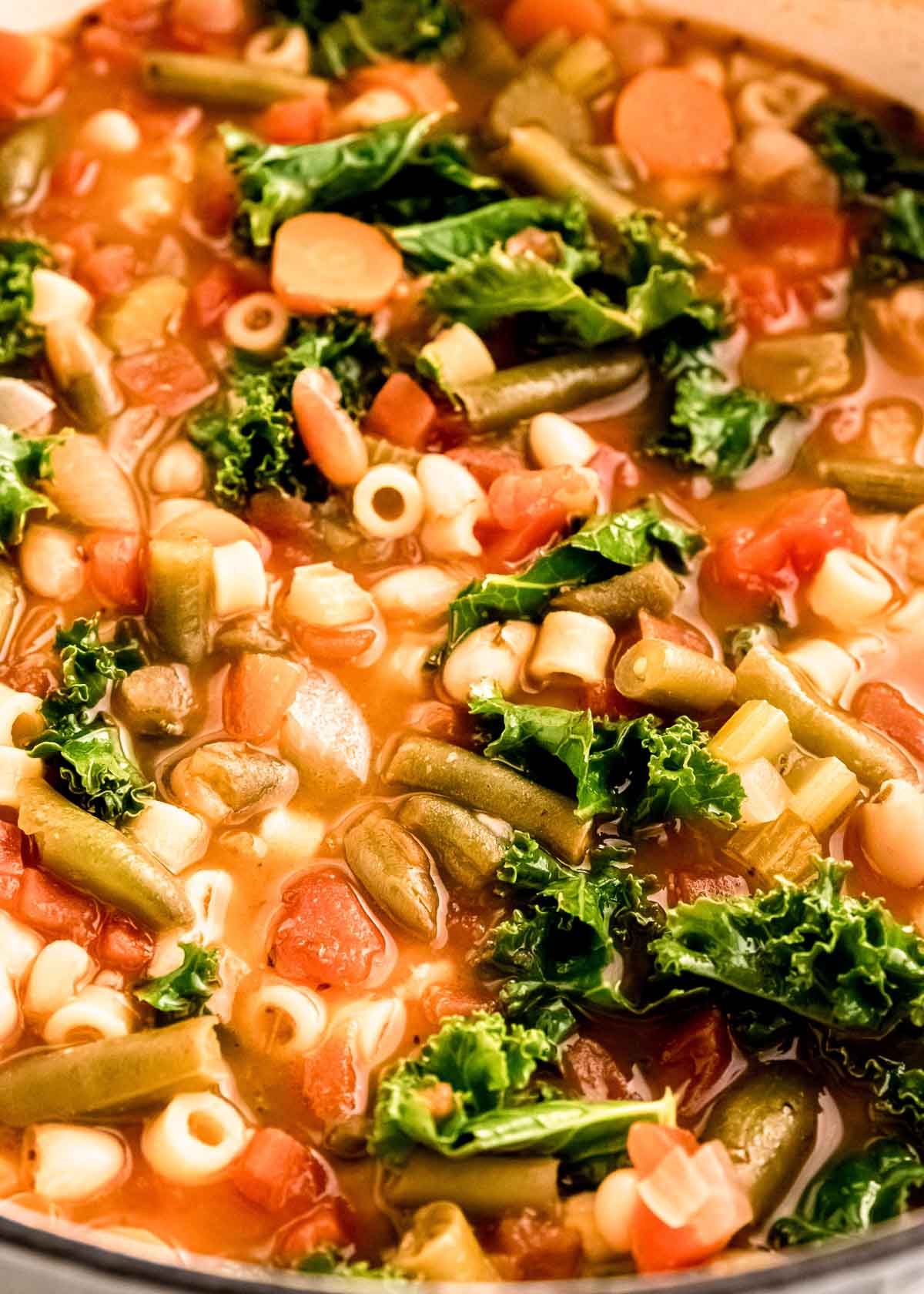 up-close shot of minestrone soup recipe with pasta, kale, beans, and tons of veggies