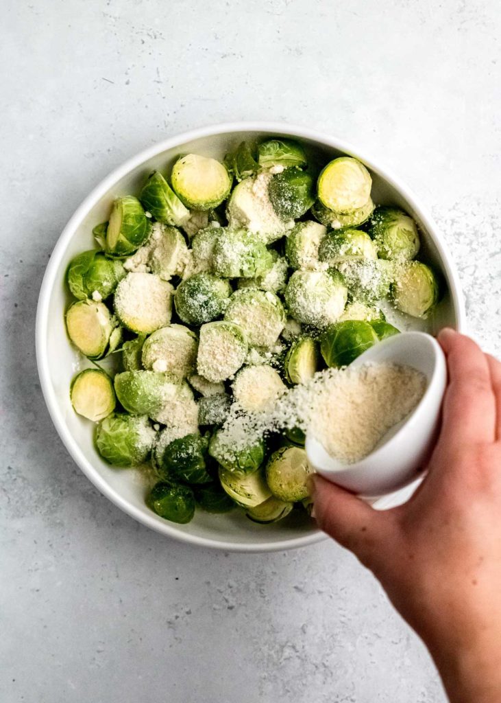parmesan sprinkled over brussels sprouts in a white bowl