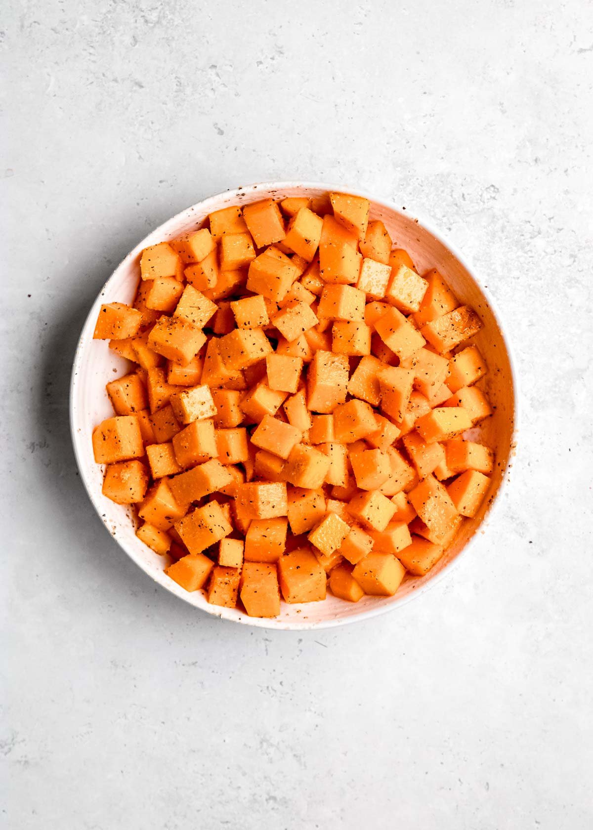 seasoned cubed butternut squash in white bowl