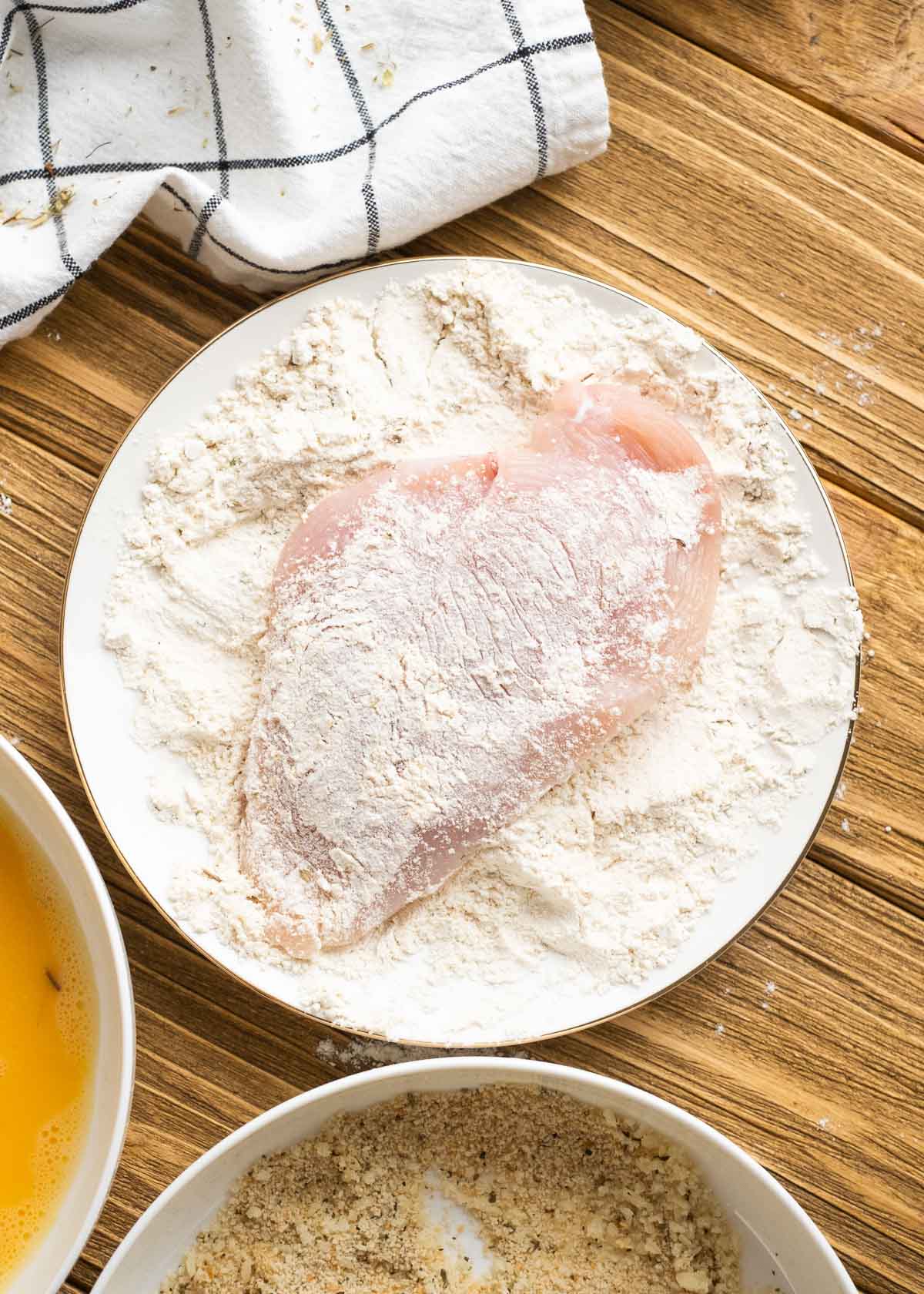 an over head shot of chicken being placed in flour