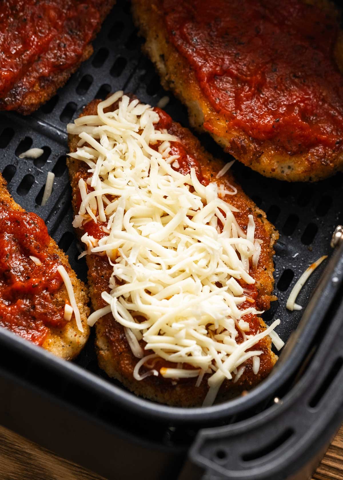 toppings being added to chicken parmesan