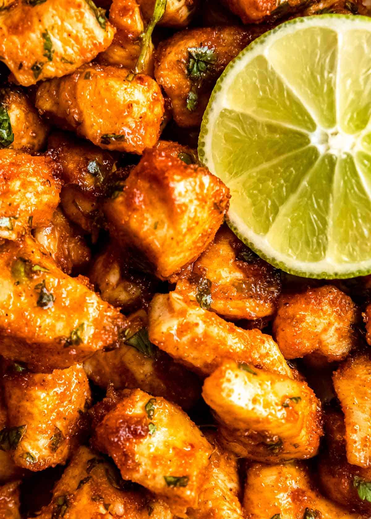 close up image of air fryer cilantro lime chicken bites and lime wedge