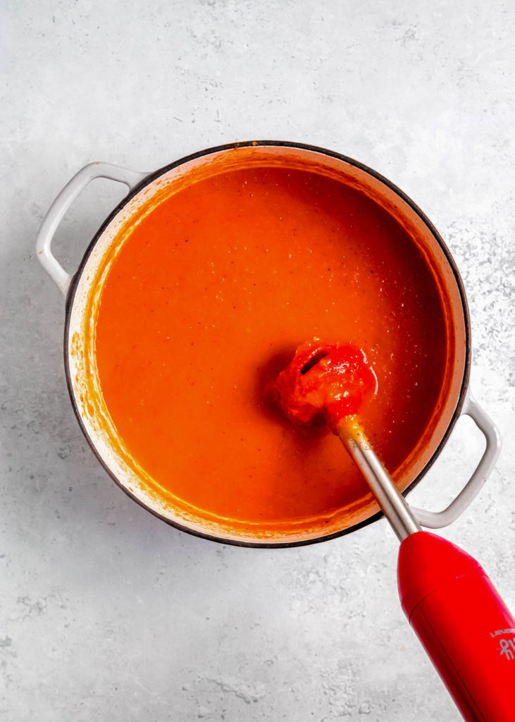 immersion blender in a pot full of roasted red pepper soup