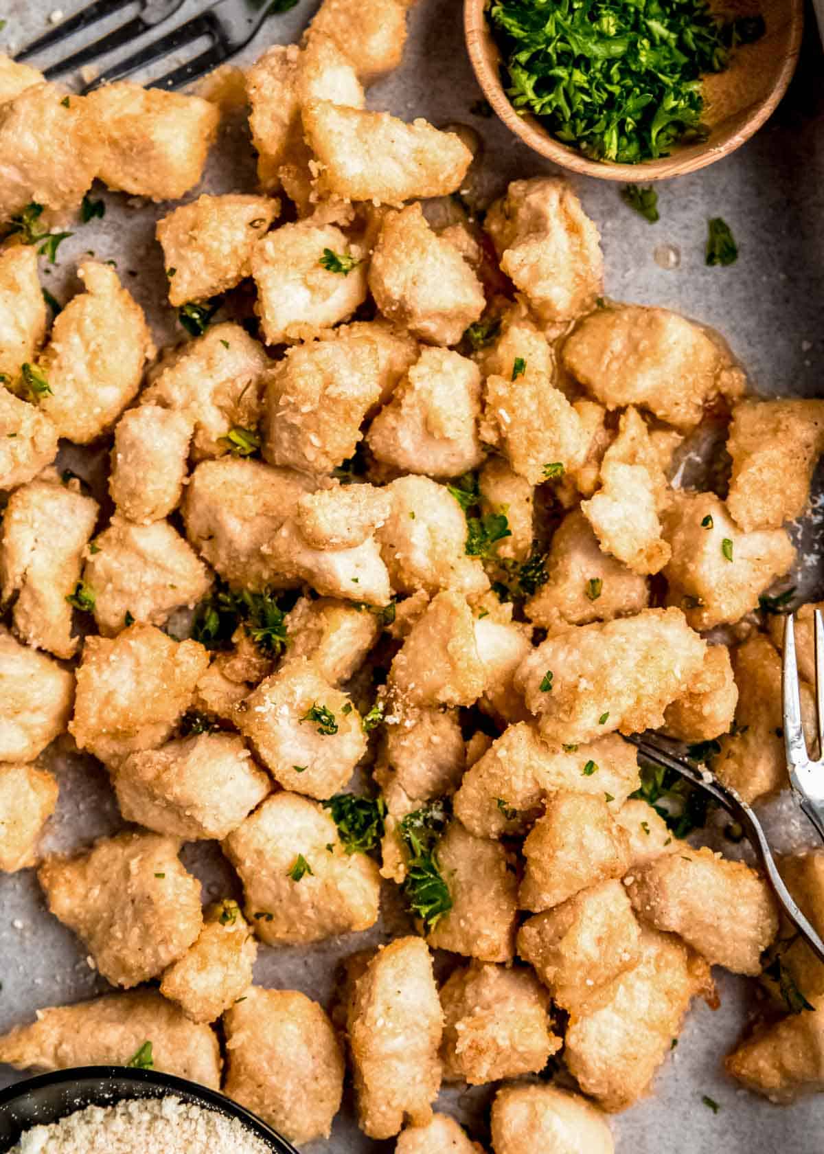 a baking sheet filled with juicy garlic parmesan chicken bites tossed in garlic butter sauce and fresh herbs