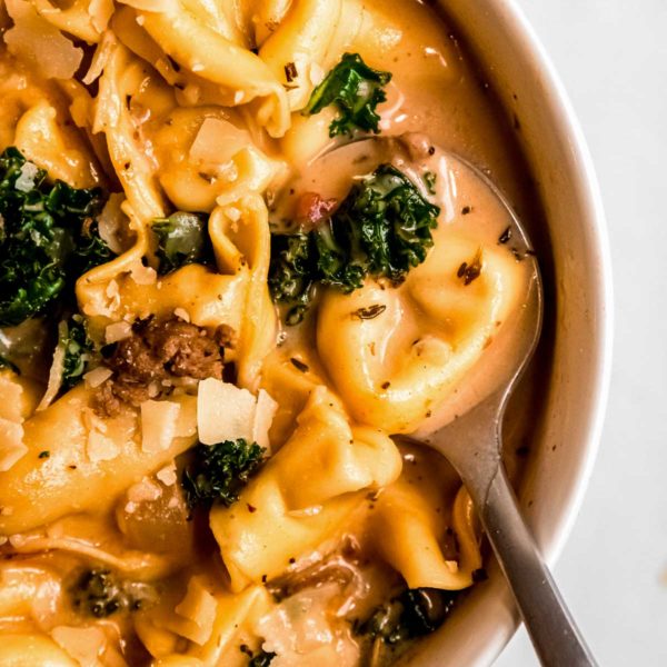 a big bowl of easy sausage tortellini soup with kale and sundried tomatoes