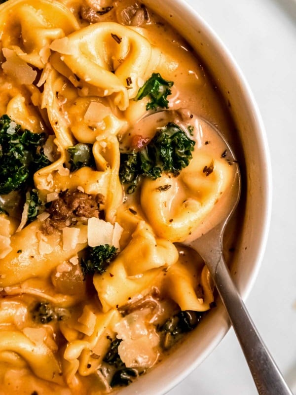 a big bowl of easy sausage tortellini soup with kale and sundried tomatoes