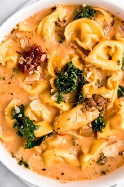 closeup shot of creamy soup with italian sausage, cheese tortellini, kale, and sundried tomatoes