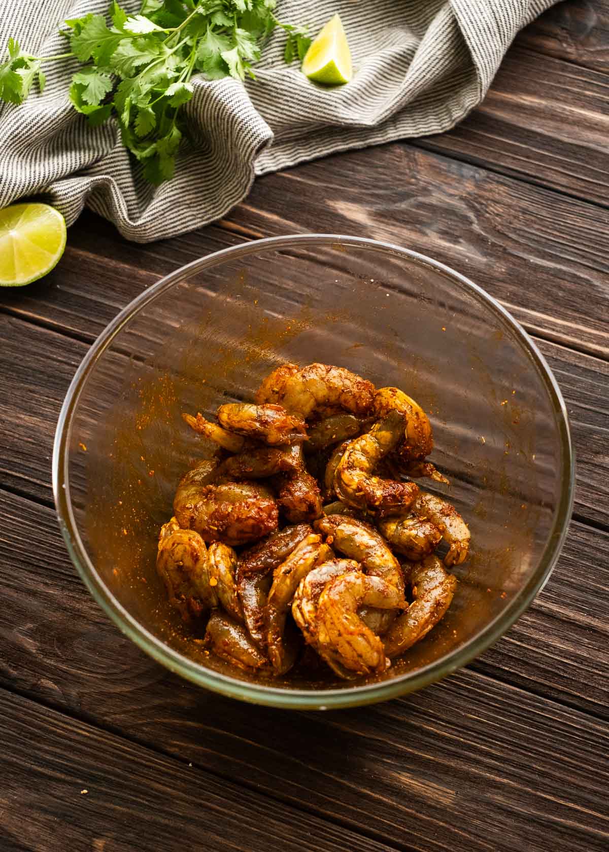 overhead image of seasoned shrimp in a clear mixing bowl