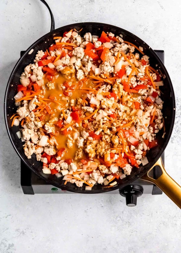 peanut sauce in a skillet with ground chicken, peppers, onion, garlic, and carrots