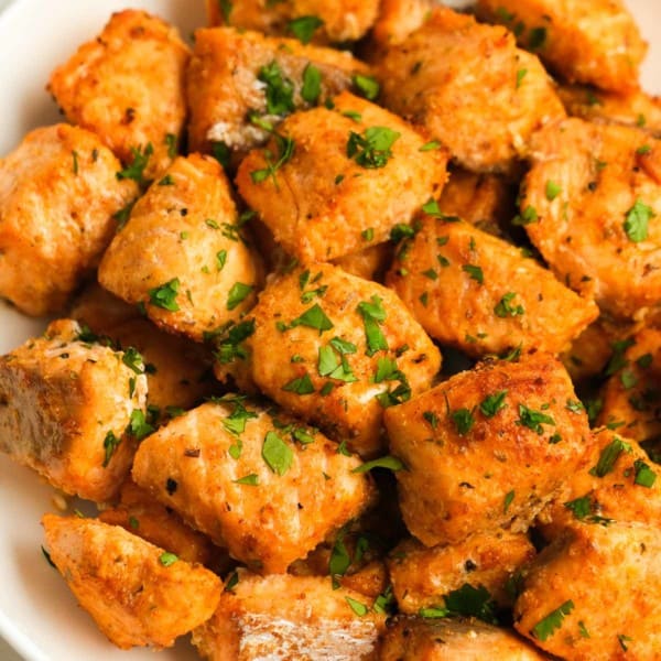 white plate full of air fryer salmon bites sprinkled with fresh herbs