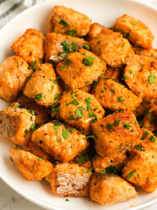 white plate full of air fryer salmon bites sprinkled with fresh herbs