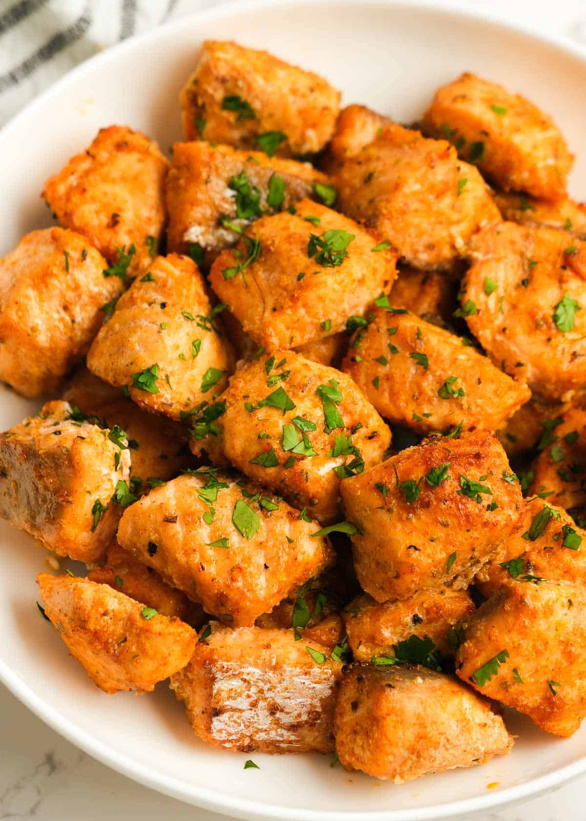 white plate full of air fryer salmon bites sprinkled with fresh herbs