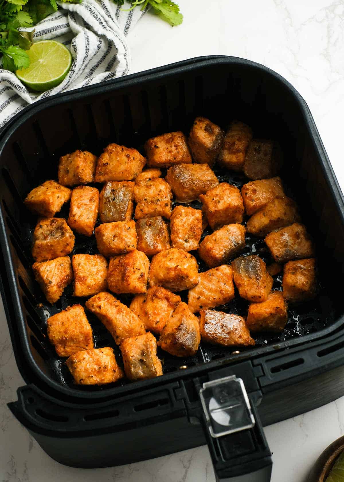 cooked salmon bites in an air fryer basket