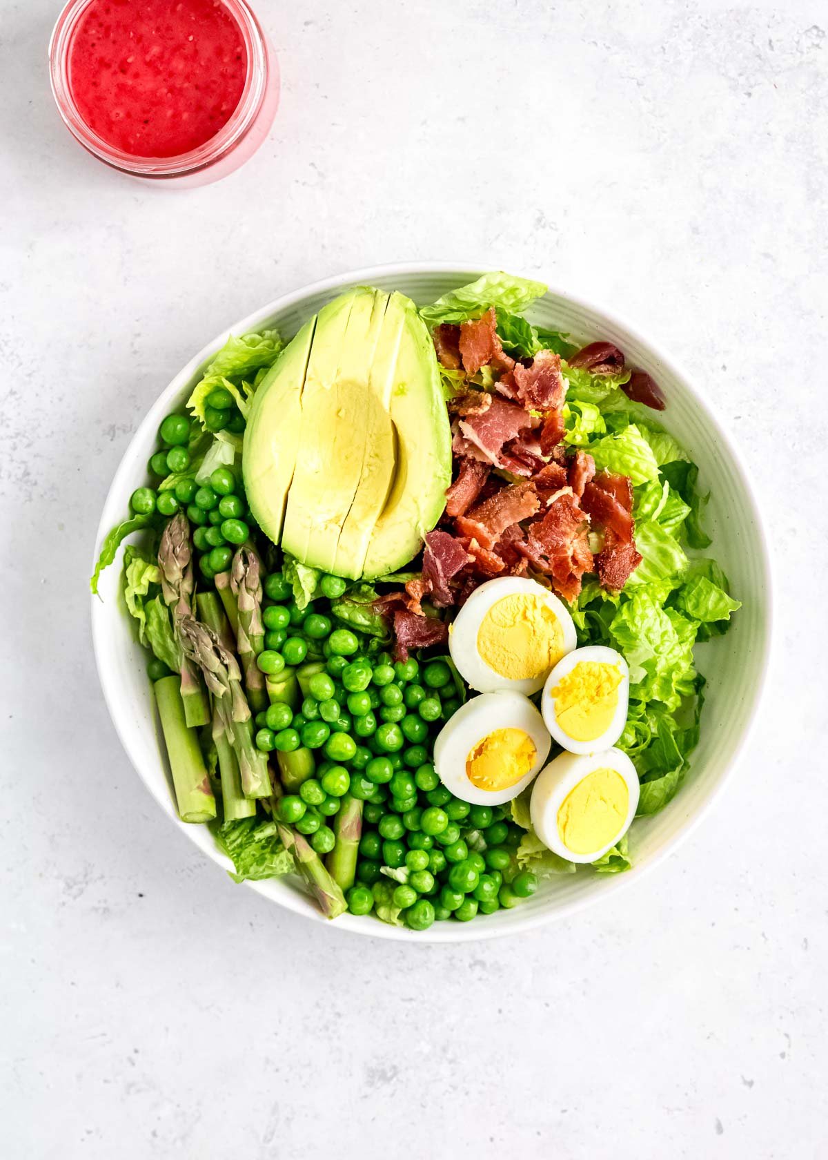 asparagus, avocado, peas, bacon, eggs, and lettuce in white bowl