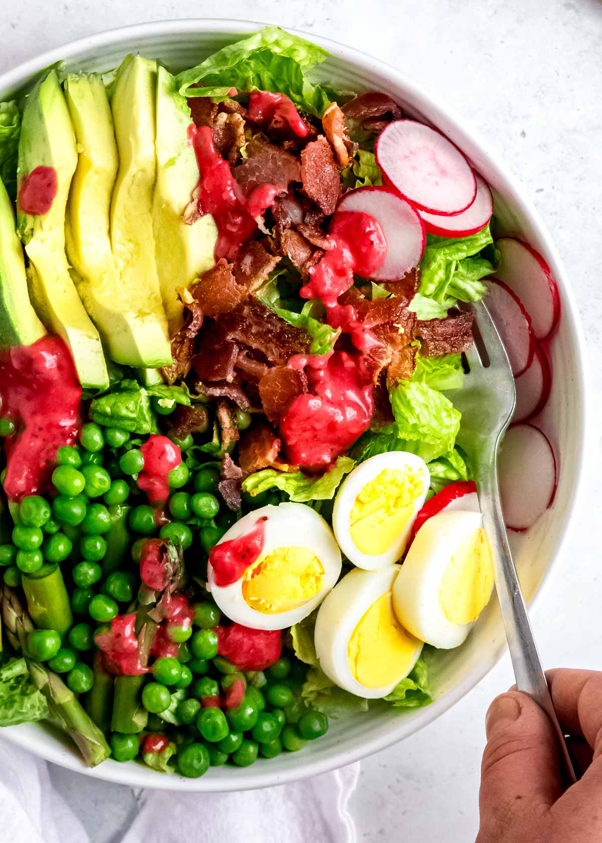 close up image of spring salad with raspberry vinaigrette in white bowl