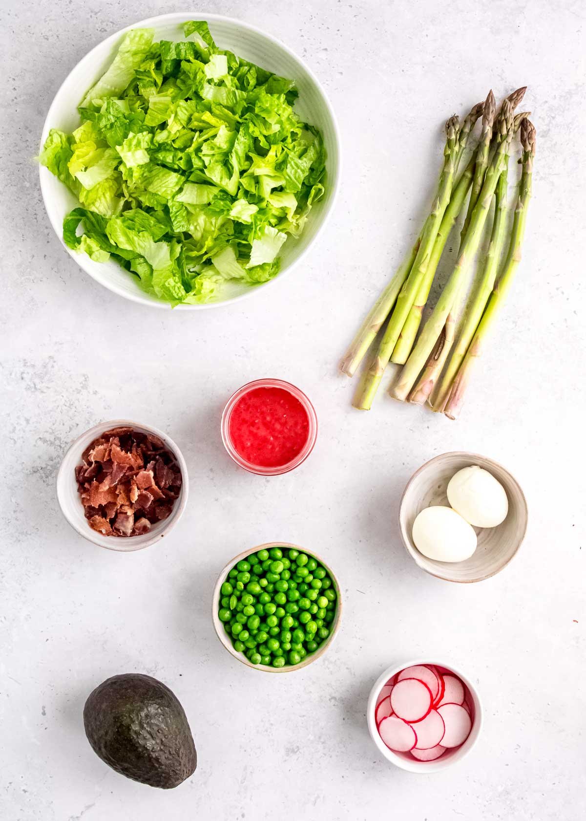 overhead image of spring salad ingredients on a white table