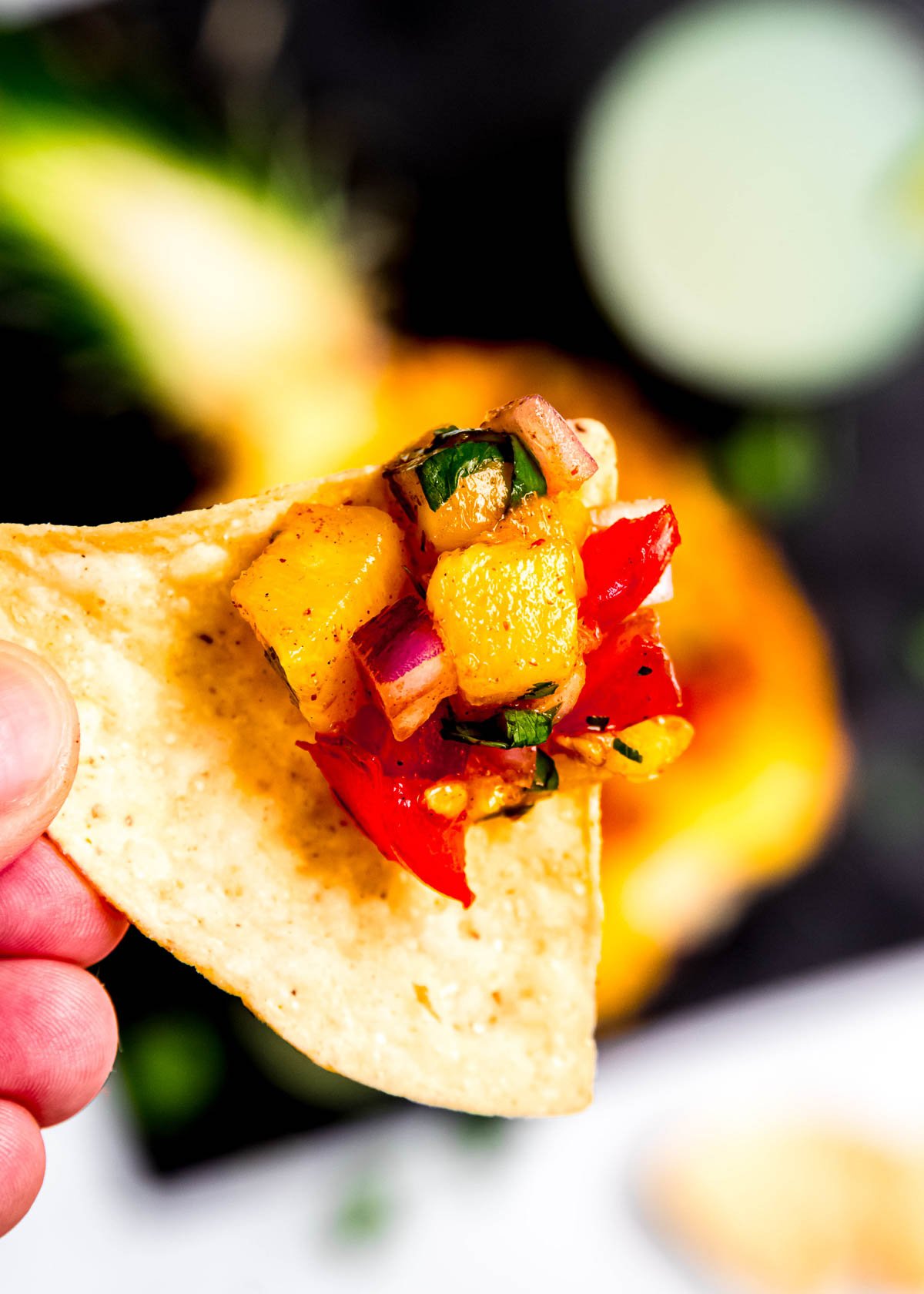 closeup view of juicy pineapple salsa on a tortilla chip