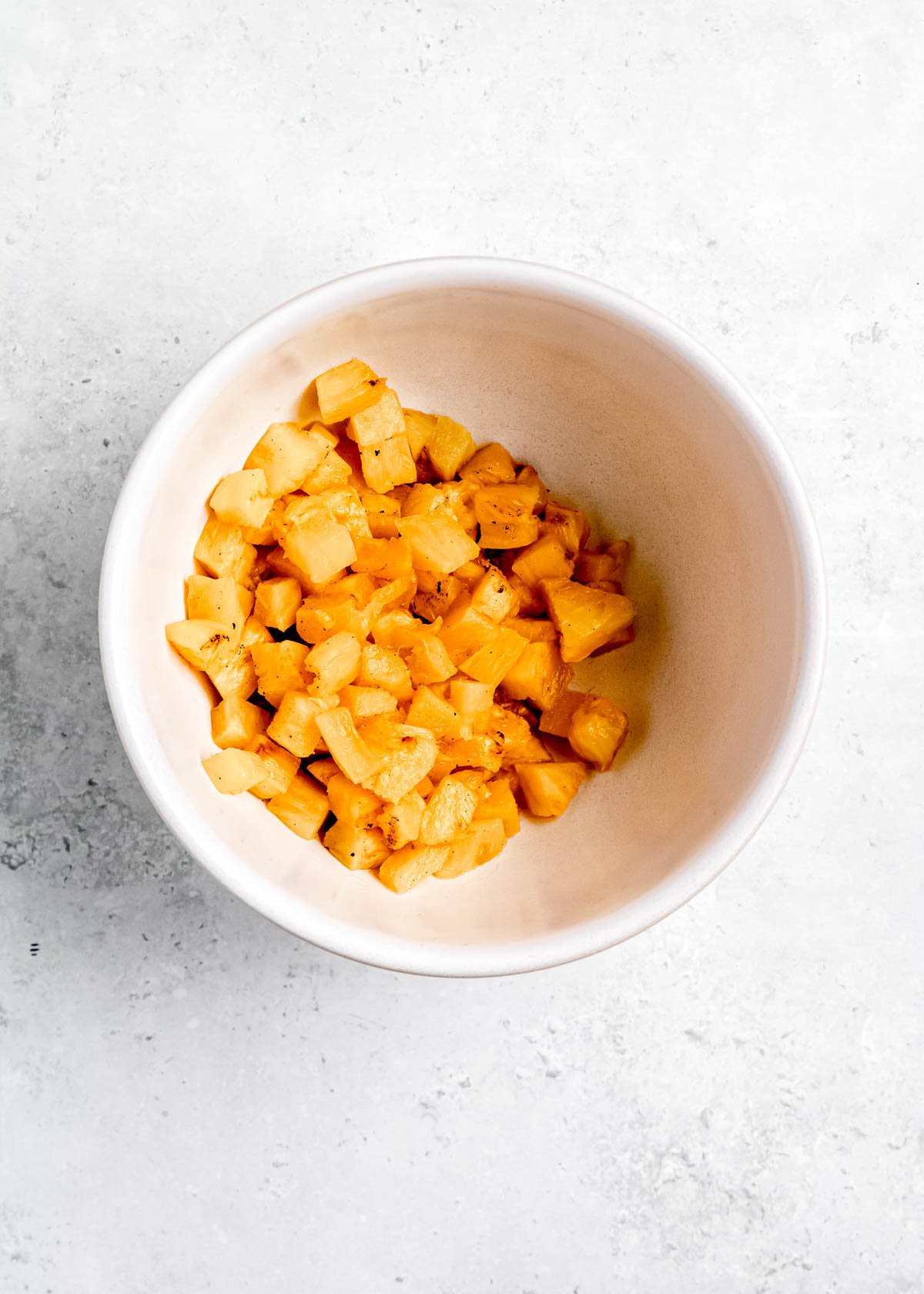 diced pineapple in a white bowl with rind removed