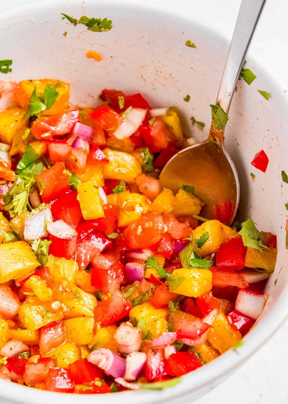 a white bowl and metal spoon with easy pineapple salsa