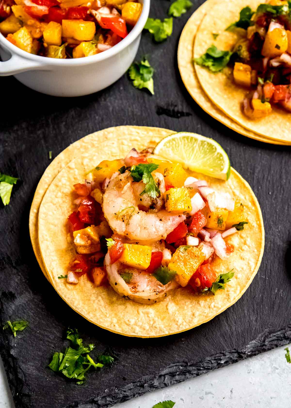 closeup shot of grilled shrimp taco with pineapple salsa and fresh limes