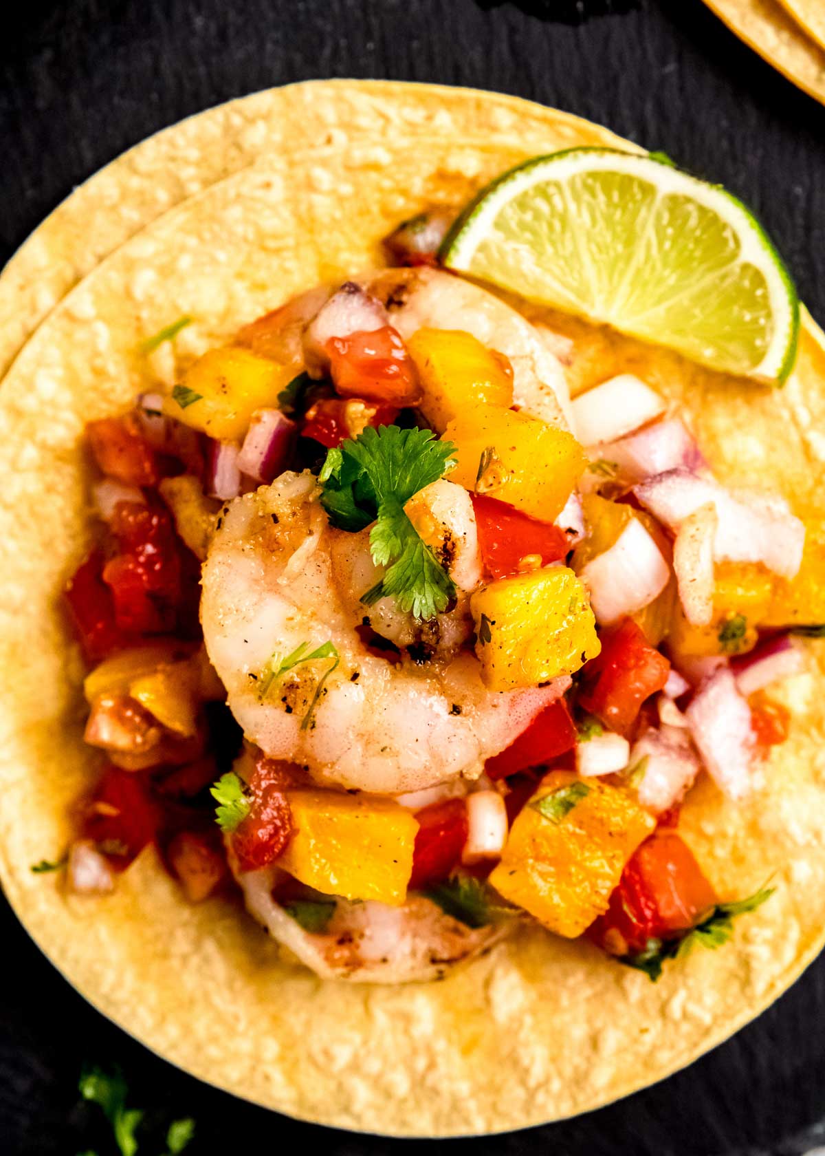 overhead closeup shot of corn tortillas loaded with juicy grilled shrimp and pineapple salsa