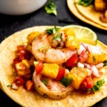 45 degree shot closeup view of juicy grilled shrimp and grilled pineapple salsa on corn tortillas