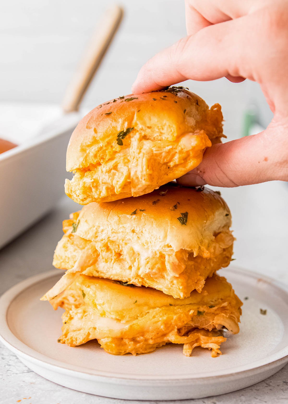 a stack of three buffalo chicken sliders on a white plate