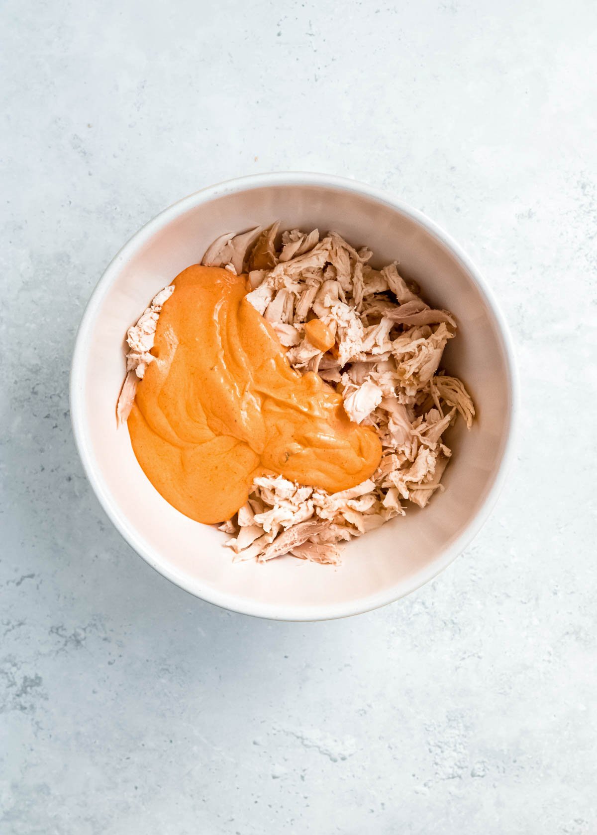 creamy buffalo sauce and shredded chicken in a white bowl