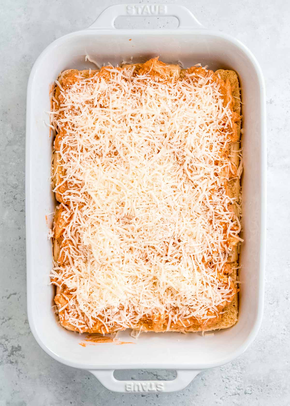 creamy buffalo chicken and shredded mozzarella on buns in a white casserole dish