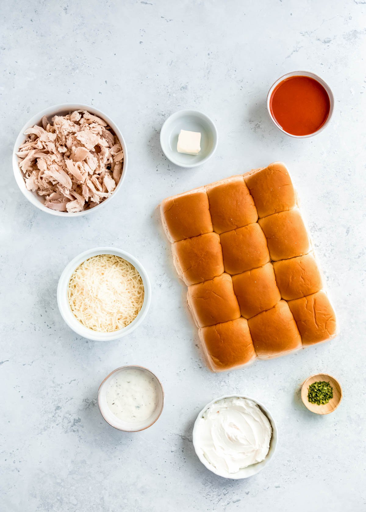 all ingredients needed for buffalo chicken sliders on a white table