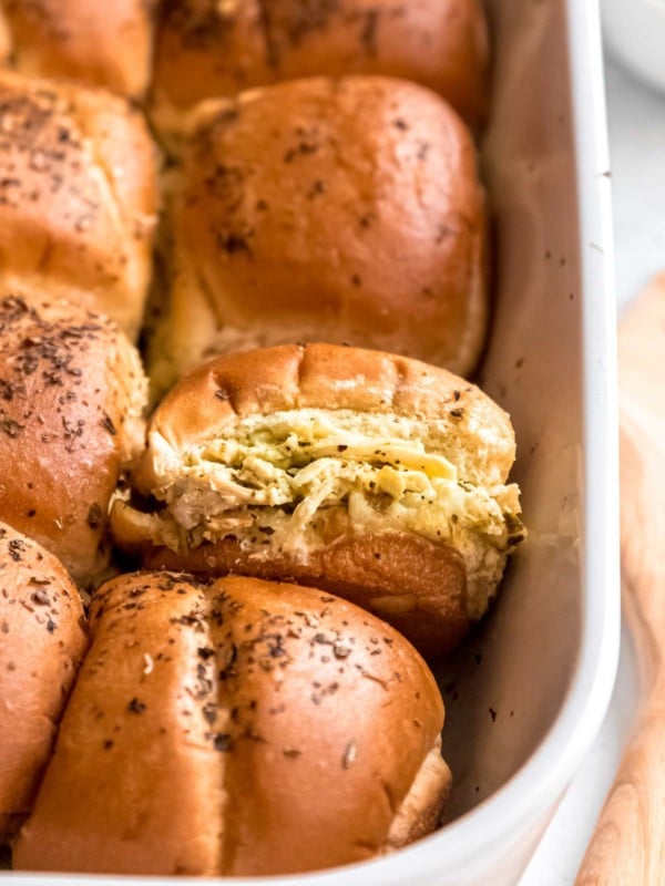 a casserole dish filled with cheesy pesto chicken sliders